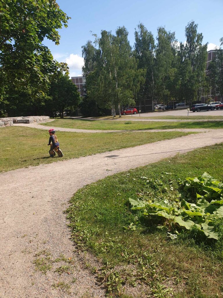 lapsi ajaa pyörällä puistossa